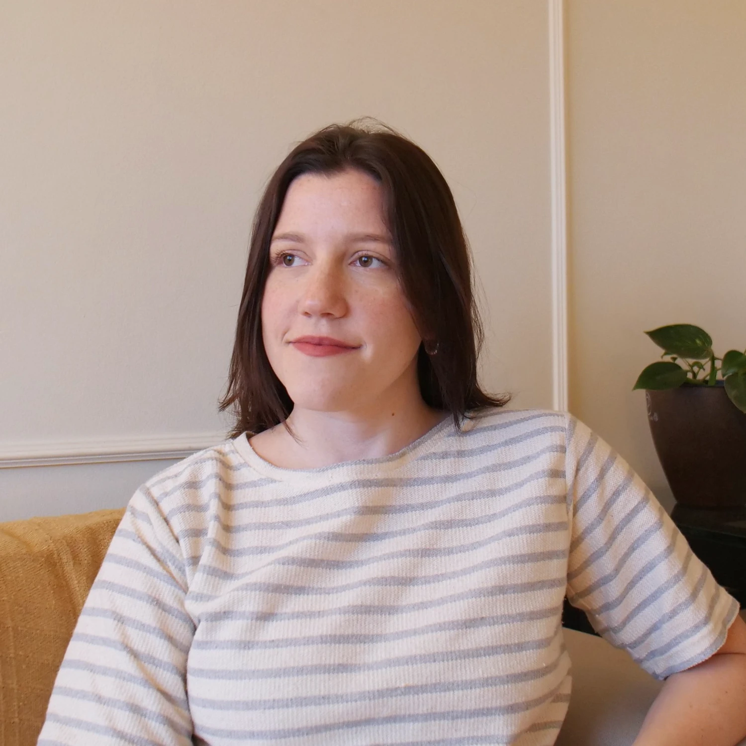 Gabriella Utrine sentada em seu consultório, com blusa clara listrada.